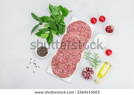 Raw burger patties. Fresh meat cutlets, spices, vegetables and herbs. Homemade American classic, traditional food for picnic, party or Independence Day. Light stone concrete background, top view