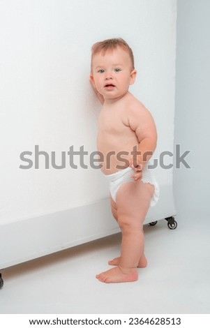 Smiling happy baby . Portrait of a little toddler boy, a baby in a diaper happily stands and laughs in isolation against the white background of the studio. The concept of childhood, motherhood, life,