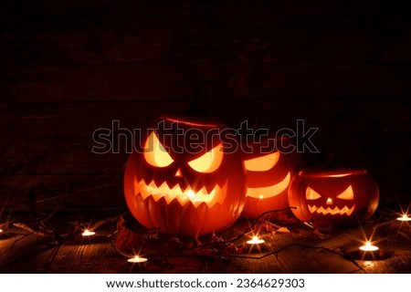 Halloween pumpkins head jack o lantern, candles and dry maple leaves in mist
