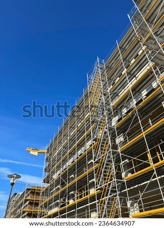 Construction site of a building in good weather. Yellow construction cranes on a working day. Construction of multi-storey buildings.