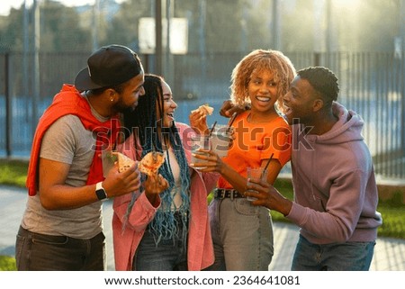Group of  smiling stylish African American friends eating pizza, drinking lemonade standing together on the street. Tasty food, friendship concept	 Royalty-Free Stock Photo #2364641081