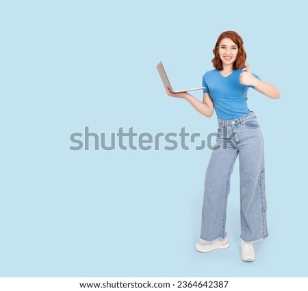Demonstrate thumb up, full body view photo of young caucasian red bob hair woman demonstrate thumb up. University student, employee, entrepreneur, copywriter holding netbook, laptop isolated blue.