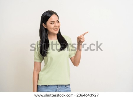 Beautiful smiling happy young asian woman in green shirt. Charming female lady pointing finger to copy space on isolated white background. Asian woman cute Pretty people looking blank space.