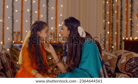 Indian mother spending quality time with her daughter during Diwali holidays. Young attractive mother explaining her daughter the meaning and concept of Diwali celebration in traditional wear