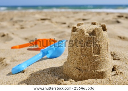closeup of a sandcastle and toy shovels of different colors on the sand of a beach Royalty-Free Stock Photo #236465536