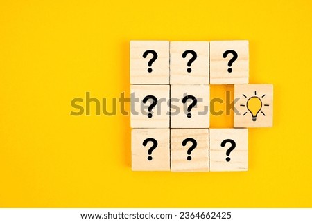 Wooden cube with hand drawn light bulb next to the cubes with question marks. Concept of problem solving, creativity, idea or innovation.