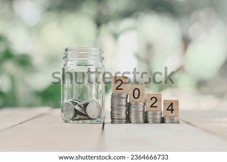 close up stack of money, 2024 wooden text block and glass bottle on wood table, saving and manage to success business, economic crisis risk and problem concept