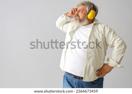Portrait of senior man in hearing protectors on grey background. Labor Day celebration Royalty-Free Stock Photo #2364673459
