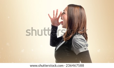 Young girl shouting over ocher background 