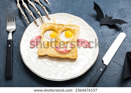 Plate with tasty Halloween sandwich, cutlery and decorations on color background