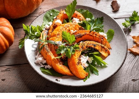 Autumn salad with grilled pumpkin, goat cheese and herbs close up. Seasonal autumn warm salad recipe, vegetarian food.