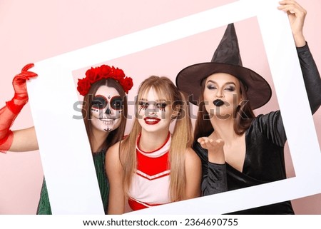 Female friends dressed for Halloween with frame on pink background