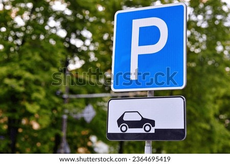 Road sign - Parking sign in the city. Parking zone for cars. Parking sign on the background of trees
