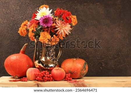 Creative autumn composition with maple leaves, pumpkins, apples, rowan berries, a bouquet of dahlias in a vase on a wooden table for a product showcase, minimal autumn concept, banner on the screen.