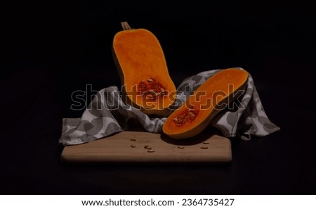 still life of sliced pumpkin parts and drapery on a black background