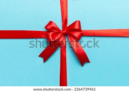 Top view of Red ribbon rolled and red bow isolated on colored background. Flat lay with copy space. Royalty-Free Stock Photo #2364739961