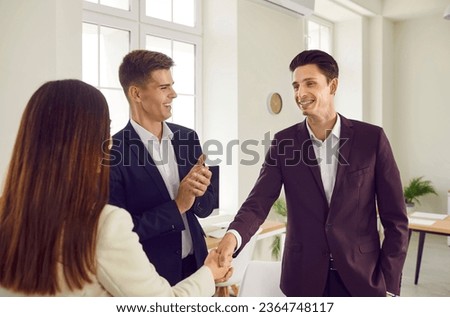 Women shaking hands with a man celebrating success, making deal, business achievement, signing contract or greeting new employee. Group of a young three business people standing in office.