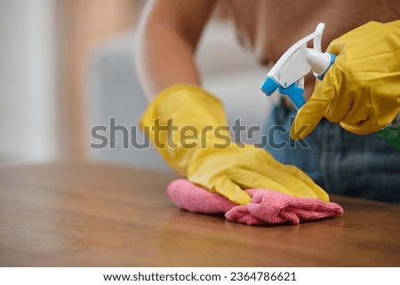Person, hands and spray bottle in cleaning or housekeeping on table for hygiene or disinfection at home. Closeup of domestic, maid or cleaner wiping furniture or desk for bacteria or germ removal Royalty-Free Stock Photo #2364786621
