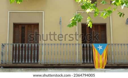 Catalan pro-independence flag formed by red and yellow stripes with blue triangle and white star on a typical balcony of a small village.