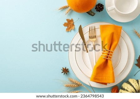 Viewed from above, a warm Thanksgiving gathering comes to life with golden dishes, cutlery and fall-themed accents adorn light blue isolated setting, designed for text or promotional content Royalty-Free Stock Photo #2364798543
