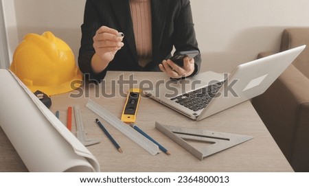 asian woman architect in shirt looking on internet online blueprint document project of green building. female interior designer worker working desktop computer monitor typing keyboard