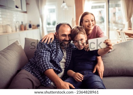 Young Caucasian family taking a selfie on a smartphone in the living room at home