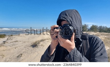 Photographer taking photos of seascape with dunes and blue sky