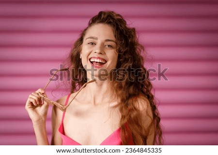 Young positive smiling woman receives a gift and holds in her hands a glasses wrapped in rustic beige craft paper