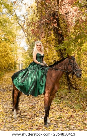 A woman in a long dress sits on a horse. Autumn forest, horse breeding. High quality photo