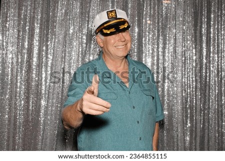 Photo Booth. Man wearing a Captains Hat. A man enjoys wearing a Captains Hat while having his pictures taken in a Photo Booth at a Party on a Yacht. People on Yachts love Photo Booths. Happy Sailing. 