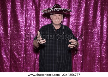 Photo Booth. A man wears a Sombrero and smiles as he waits for his pictures to be taken while enjoying a Photo Booth at a Wedding or Party. People love Photo Booths and get pictures printed instantly.