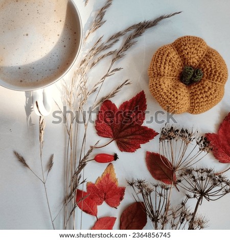 Autumn still life with a cup of coffee, spikelets, rosehip, dried flowers, leaves, crocheted pumpkin
