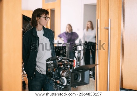The director is a woman at work on the set. The director works with a group or with a playback while filming a movie, advertising, or a TV series. Shooting shift, equipment and group. 