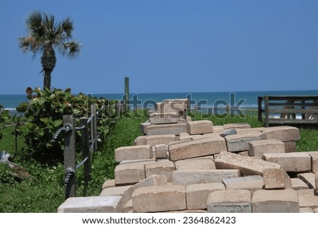 Pile of brick pavers stacked on grass near beach.