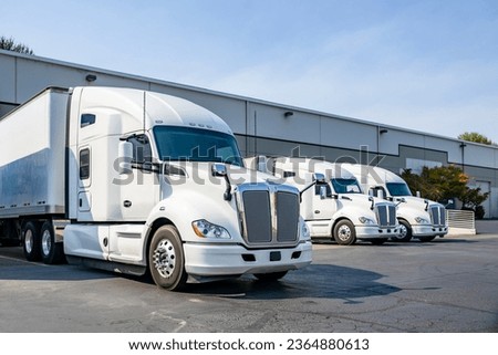 Industrial long hauler carriers white big rig semi trucks tractors with high cab for truck driver rest standing on the parking lot in warehouse docks gates loading cargo for the next delivery freight Royalty-Free Stock Photo #2364880613