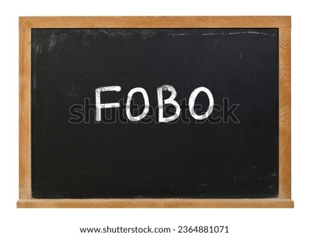 FOBO written in white chalk on a black chalkboard isolated on white Royalty-Free Stock Photo #2364881071