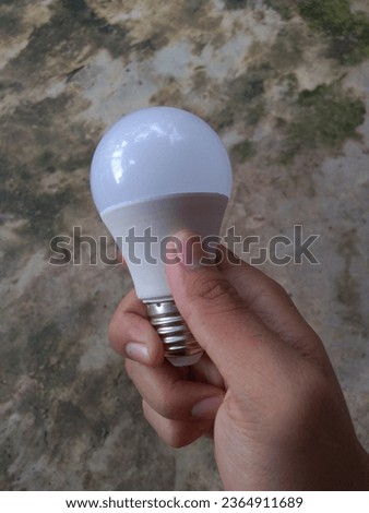 Asian man's hand holding a light bulb