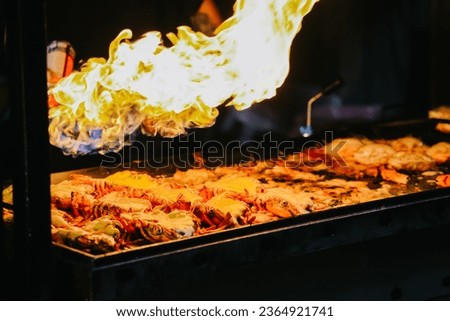 Close-up of flame fire burn lobter with cheese for serve from popular Korea street food at Dongmun night market, Jeju Island. Royalty-Free Stock Photo #2364921741