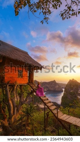 Happy and relaxed travel woman watching sunrise, tree house with diamond beach, Atuh beach in Nusa Penida island, Bali, Indonesia. Royalty-Free Stock Photo #2364943603
