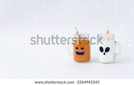 On a light background there are charming, funny glasses in the shape of ghosts with drinks for the Halloween holiday.  Halloween holiday concept, treat, copy space for text.