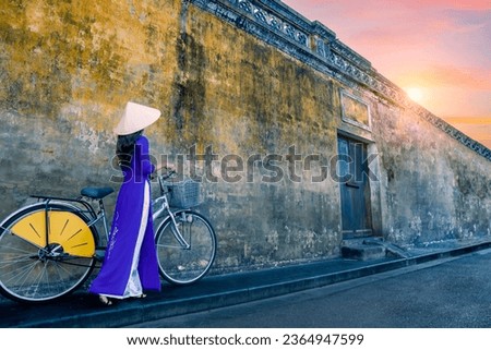 Asian woman in traditional Vietnamese costume with bicycle in Vietnam walking street Royalty-Free Stock Photo #2364947599