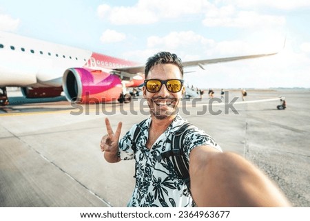 Happy young man taking selfie picture with smart mobile phone boarding on air plane - Cheerful tourist standing at the airport - Travel life style concept with smiling guy going on summer vacation
