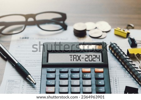 Word Tax 2024 on the calculator. Business and tax concept.Calculator, coins, book, form, and pen on table.Tax deduction planning.Financial research, government taxes, and calculation tax return Royalty-Free Stock Photo #2364963901