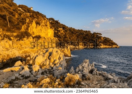 Rocks and cliffs shoreline sunset landscape of Cap Ferrat cape hosting Saint-Jean-Cap-Ferrat resort town on at French Riviera of Mediterranean Sea near Nice in France