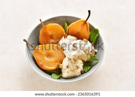 Ice cream with poached pears and nuts in bowl over light stone background. Close up view