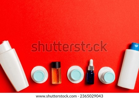 Top view of means for face care: bottles and jars of tonic, micellar cleansing water, cream, cotton pads on colored background. Bodycare concept with empty cpace for your ideas.