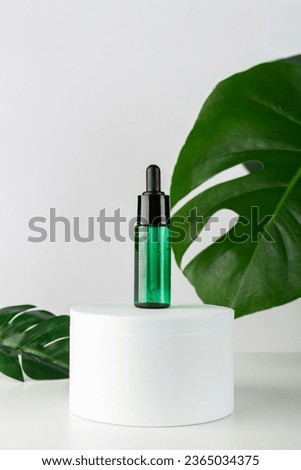 Dropper mockup with essential oil or serum on a stepped stand for product photography of cosmetics or accessories with large tropical monstera leaves.
