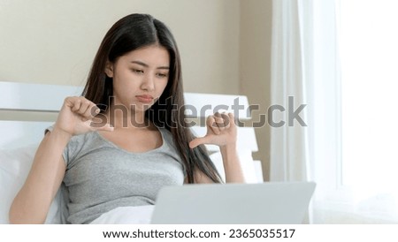 Young beautiful woman sitting on the bed and using laptop computer, she acting with thump down feel upset, copy space Royalty-Free Stock Photo #2365035517