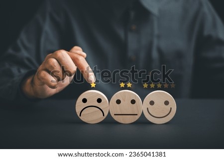 Negative customer experience concept. Hand holding wooden block with sad face icon on circle wooden table, symbolizing unhappiness and bad service. Dissatisfied client expressing dissatisfaction. Royalty-Free Stock Photo #2365041381