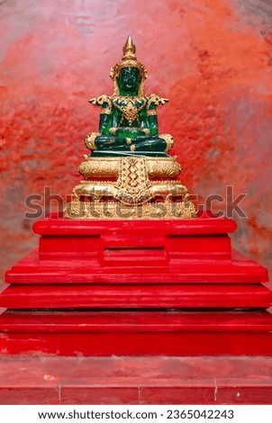 Emeral Buddha on a red wooden pedestal

